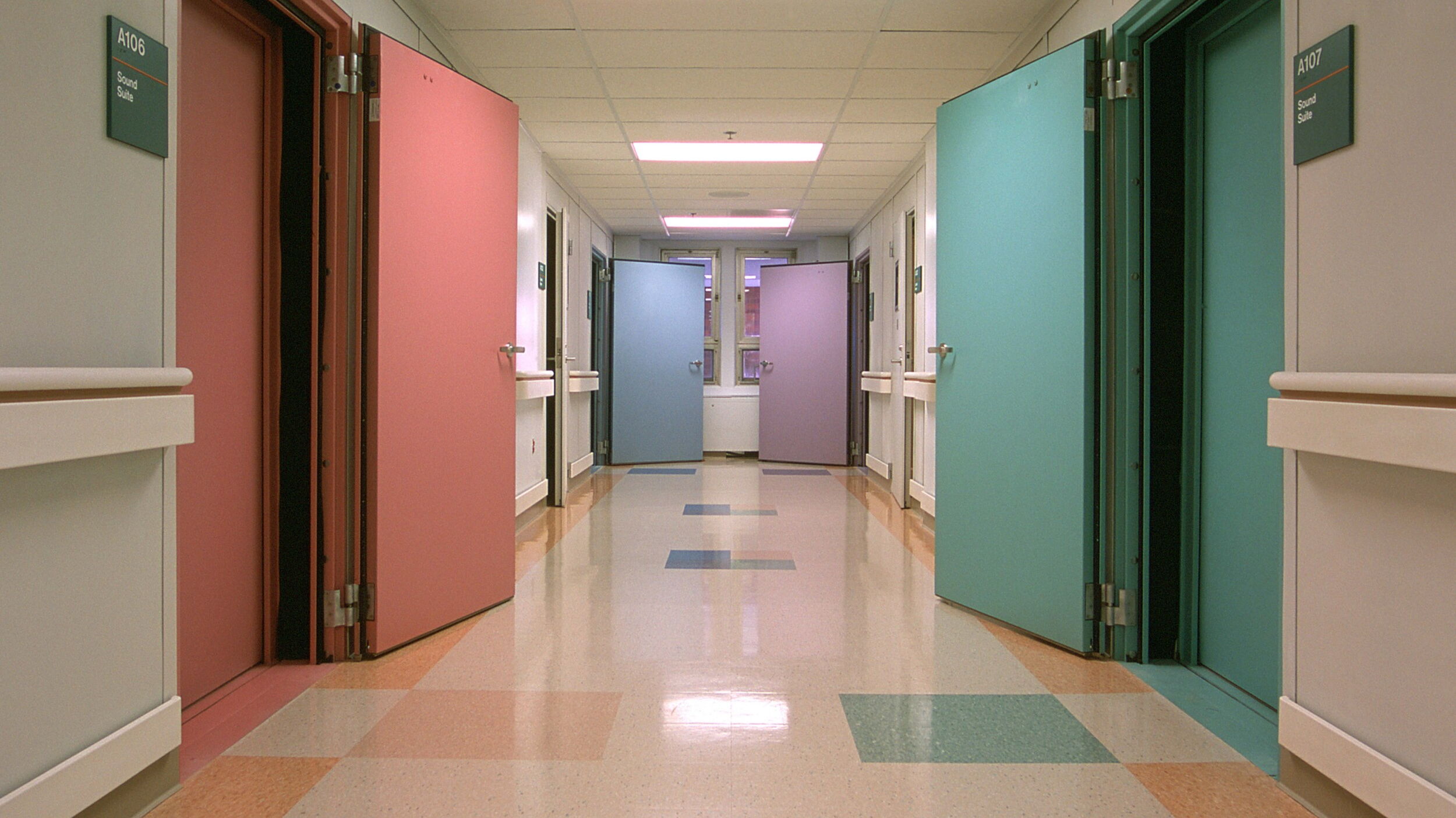 Colorful hospital corridor featuring open doors to exam rooms.