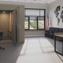 Modern office space with soundproof booth and world map decor.