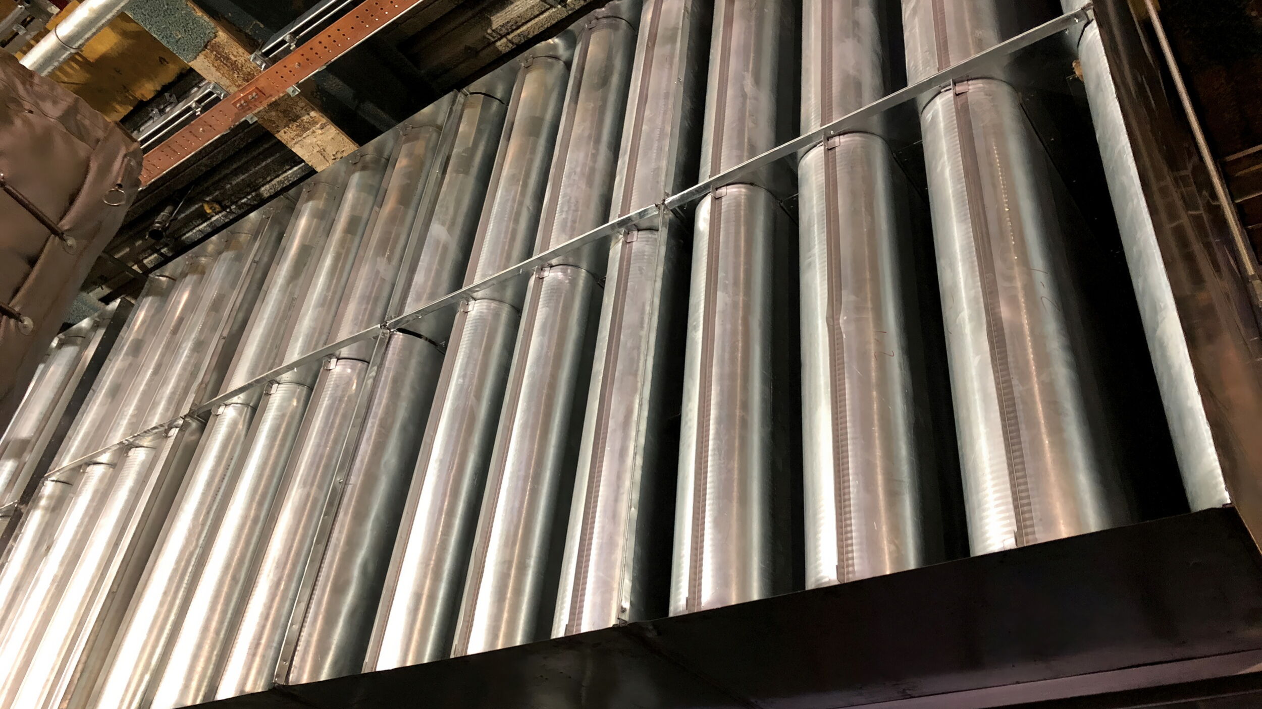 Metal pipes arranged in rows on an industrial ceiling.