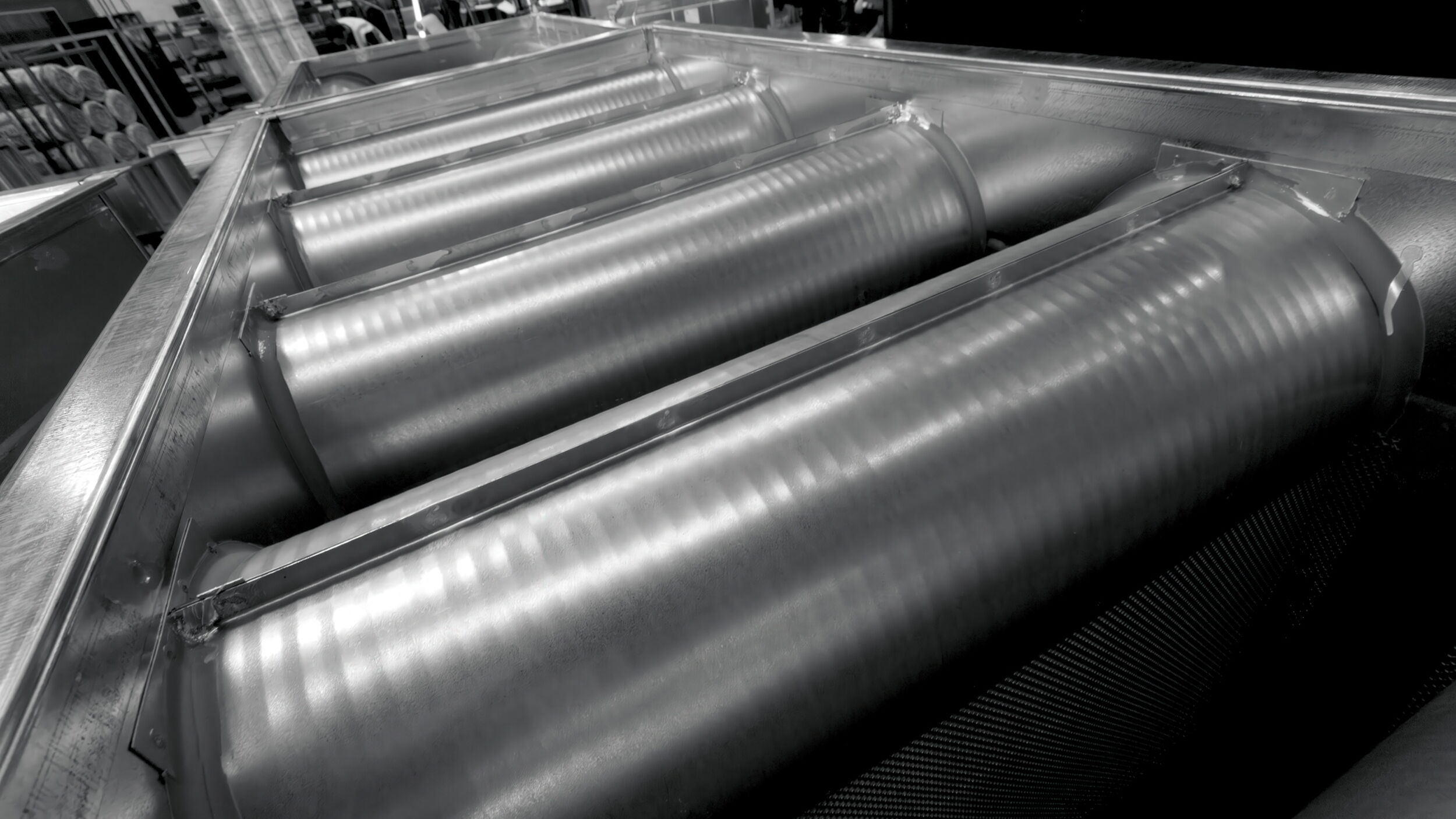 Industrial machinery featuring cylindrical metal rollers in a manufacturing environment.