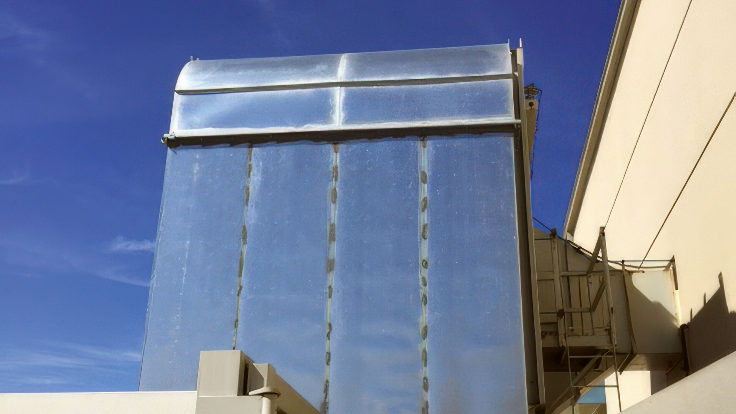 Modern building with reflective surface against a clear blue sky.