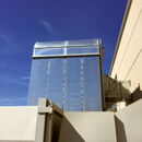 Modern building with reflective surface against a clear blue sky.