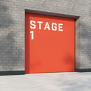 Orange stage door labeled "Stage 1" on gray brick wall.