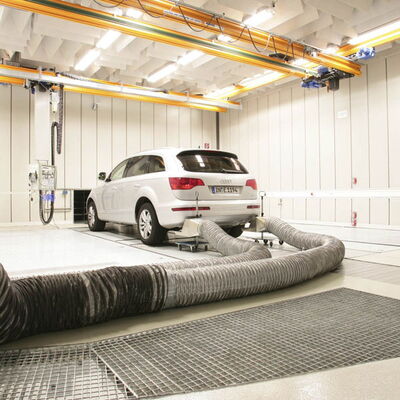 Audi vehicle in a modern automotive testing facility with exhaust extraction system.