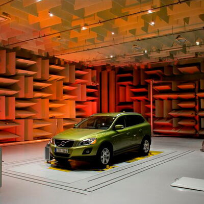 Green SUV in an anechoic chamber with colorful sound-absorbing panels.