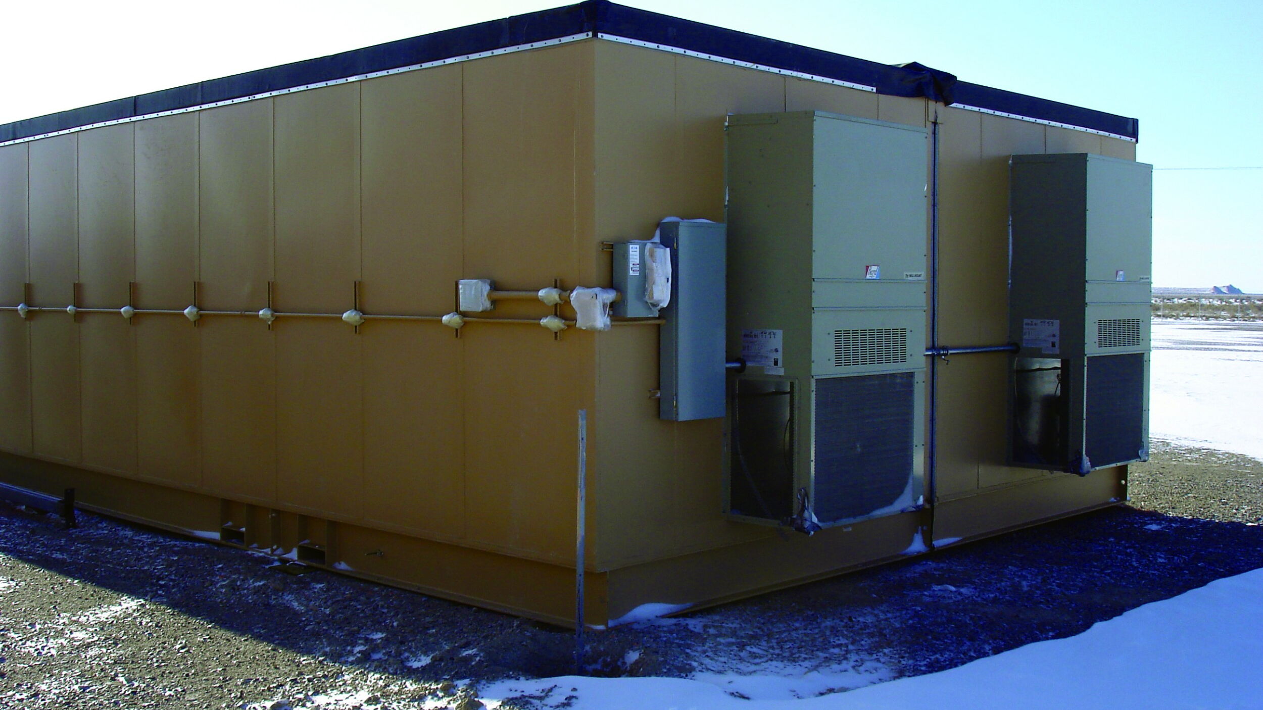 Yellow industrial container with cooling units in snowy landscape.