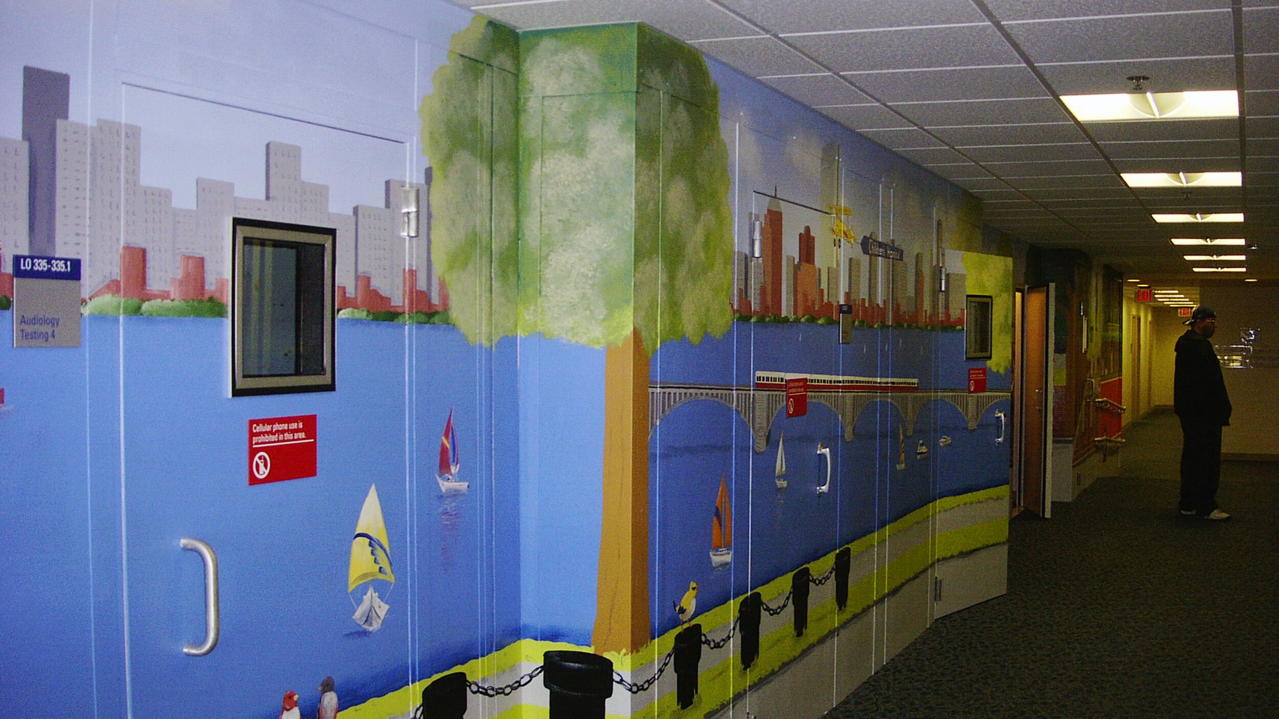 Colorful mural depicting a waterfront scene in a hospital hallway.