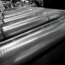 Industrial machinery featuring cylindrical metal rollers in a manufacturing environment.