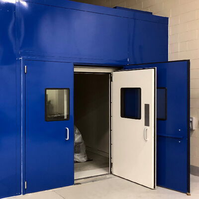 Two large doors of a blue industrial chamber open to reveal interior space.
