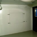 Minimalistic room with a black door and ventilation features.