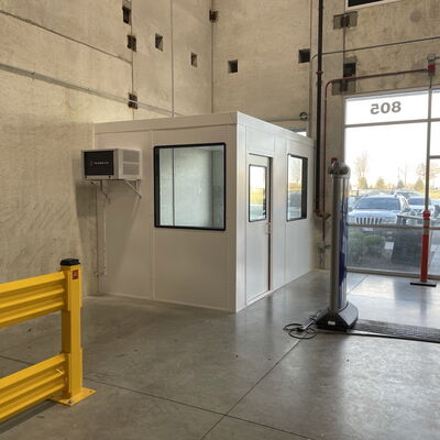 Security booth installation in large modern building entrance with yellow barriers.