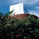 Modern architecture surrounded by lush greenery under a clear blue sky.