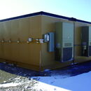 Yellow industrial container with cooling units in snowy landscape.