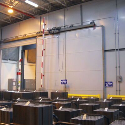 Warehouse interior with machinery and stacked equipment in a storage area.