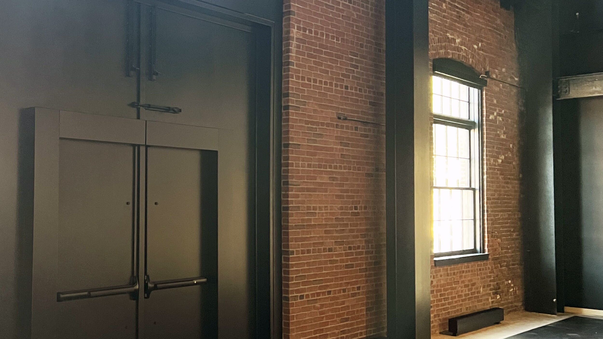 Modern industrial interior with black doors and exposed brick walls.