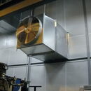 Industrial ventilation fan mounted on a metal wall in a factory setting.