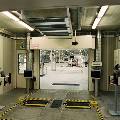 Industrial facility entrance with monitoring equipment and safety markings.